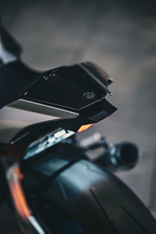 Free Detailed view of a motorcycle tail featuring a carbon fiber component with orange highlights. Stock Photo