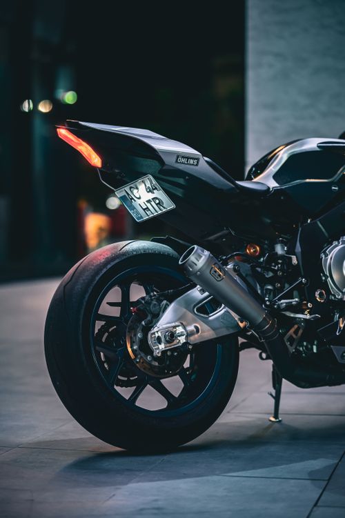 Free Close-up rear view of a sleek black motorcycle highlighting its design and rear lighting at night. Stock Photo