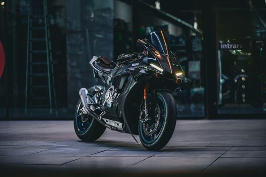 A modern black motorcycle parked in a dimly lit urban environment, showcasing its sleek design.