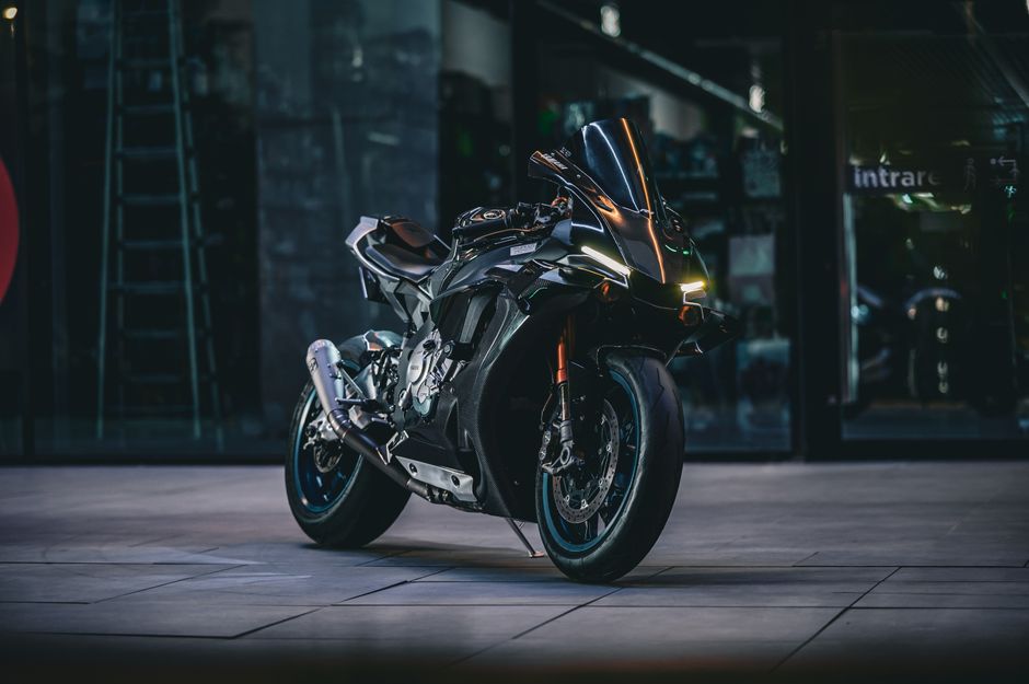 A modern black motorcycle parked in a dimly lit urban environment, showcasing its sleek design.