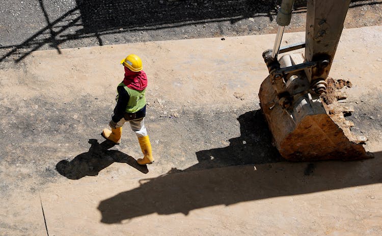 High Angle Photo Of Person Walking Near Backhoe