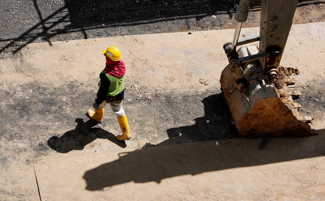 Worker beside heavy construction equipment