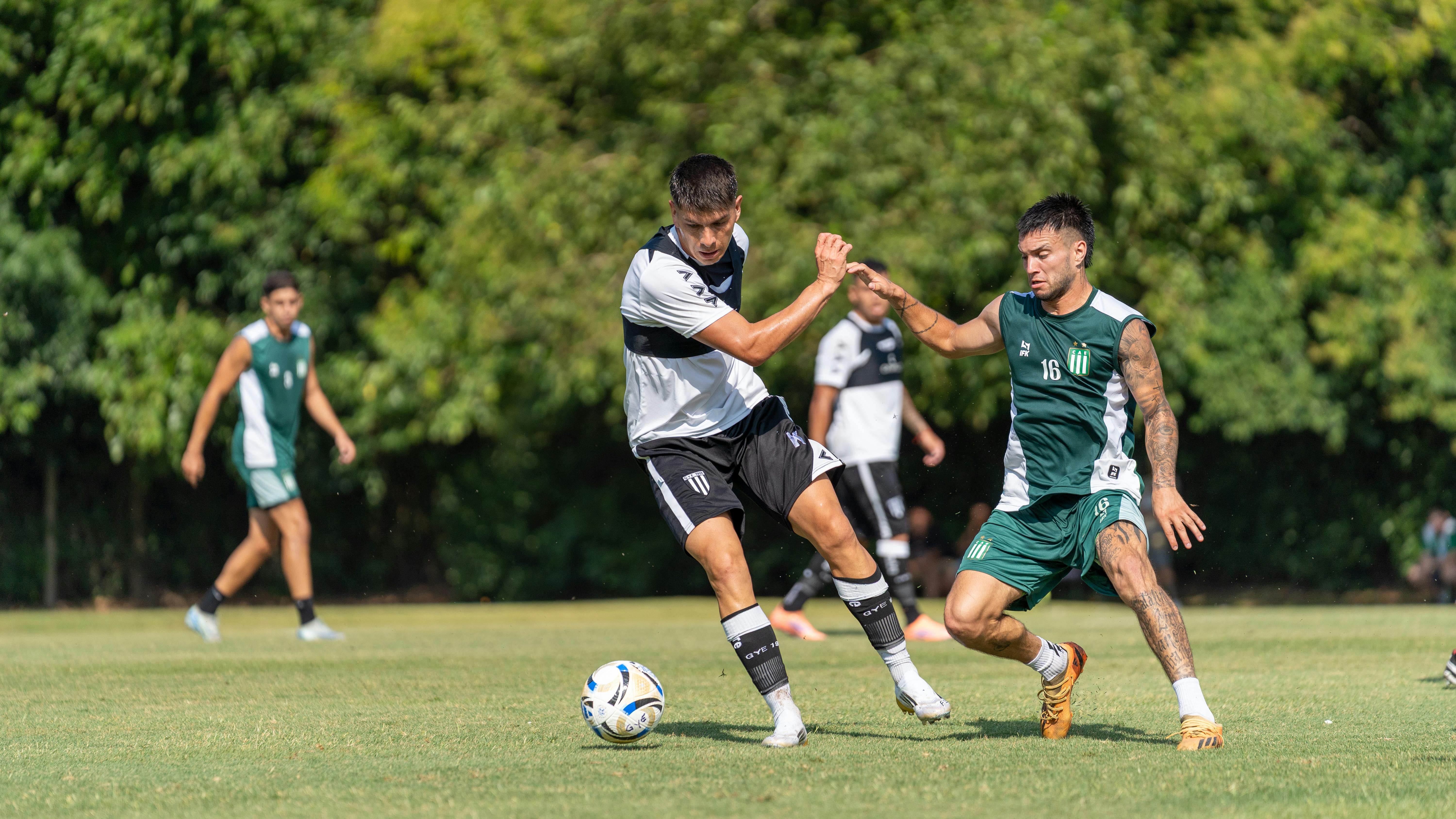 Players engaging in a competitive soccer match outdoors on a sunny day.