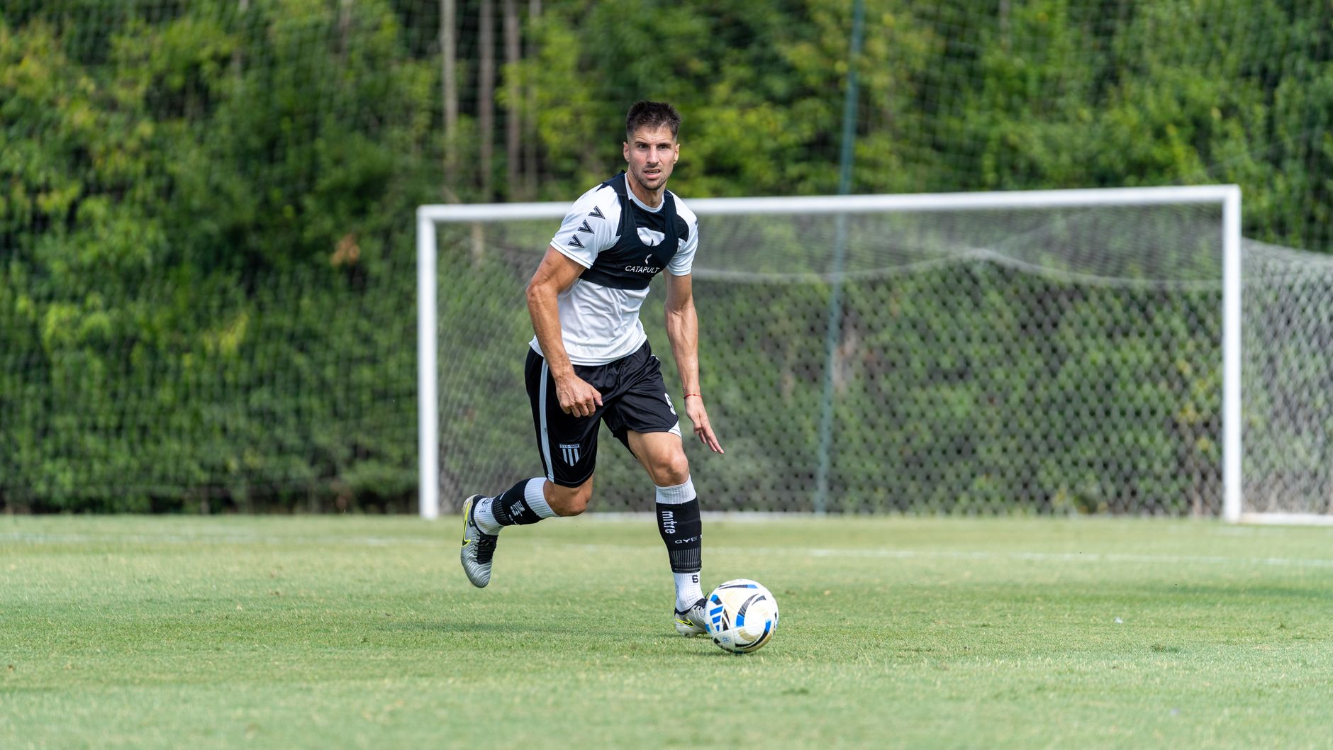 Soccer player dribbling the ball during practice outdoors on a sunny day.