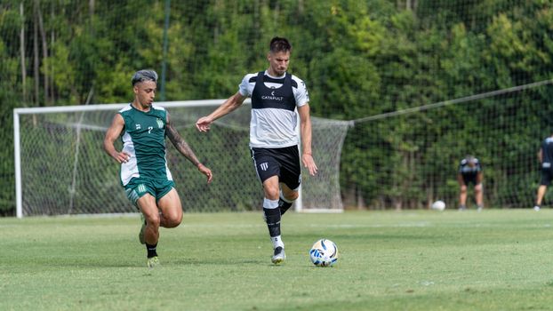Two male soccer players competing on a grassy field during a daytime match.