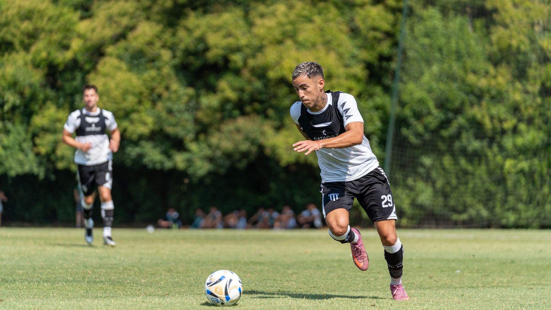 Soccer player energetically chasing the ball during a match on a sunny day.
