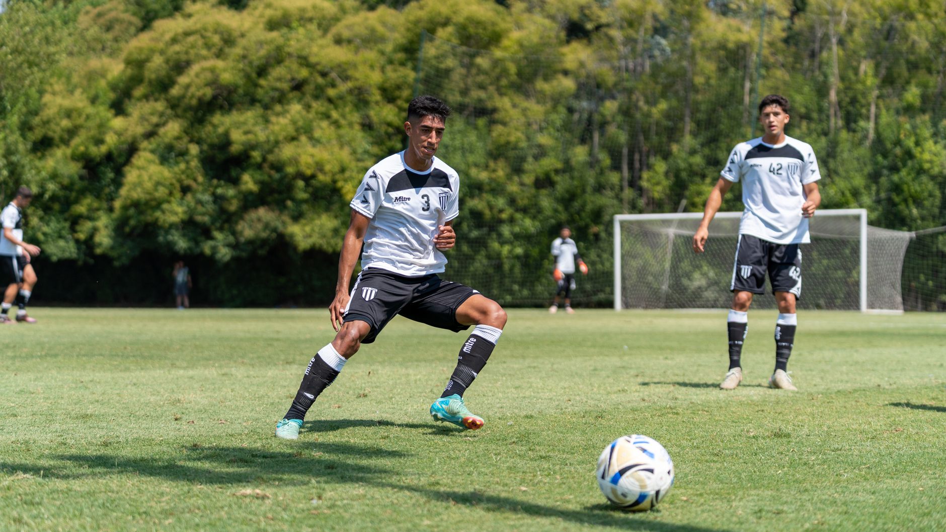 winger sprinting toward midfield as defenders clear a second ball from a packed penalty area