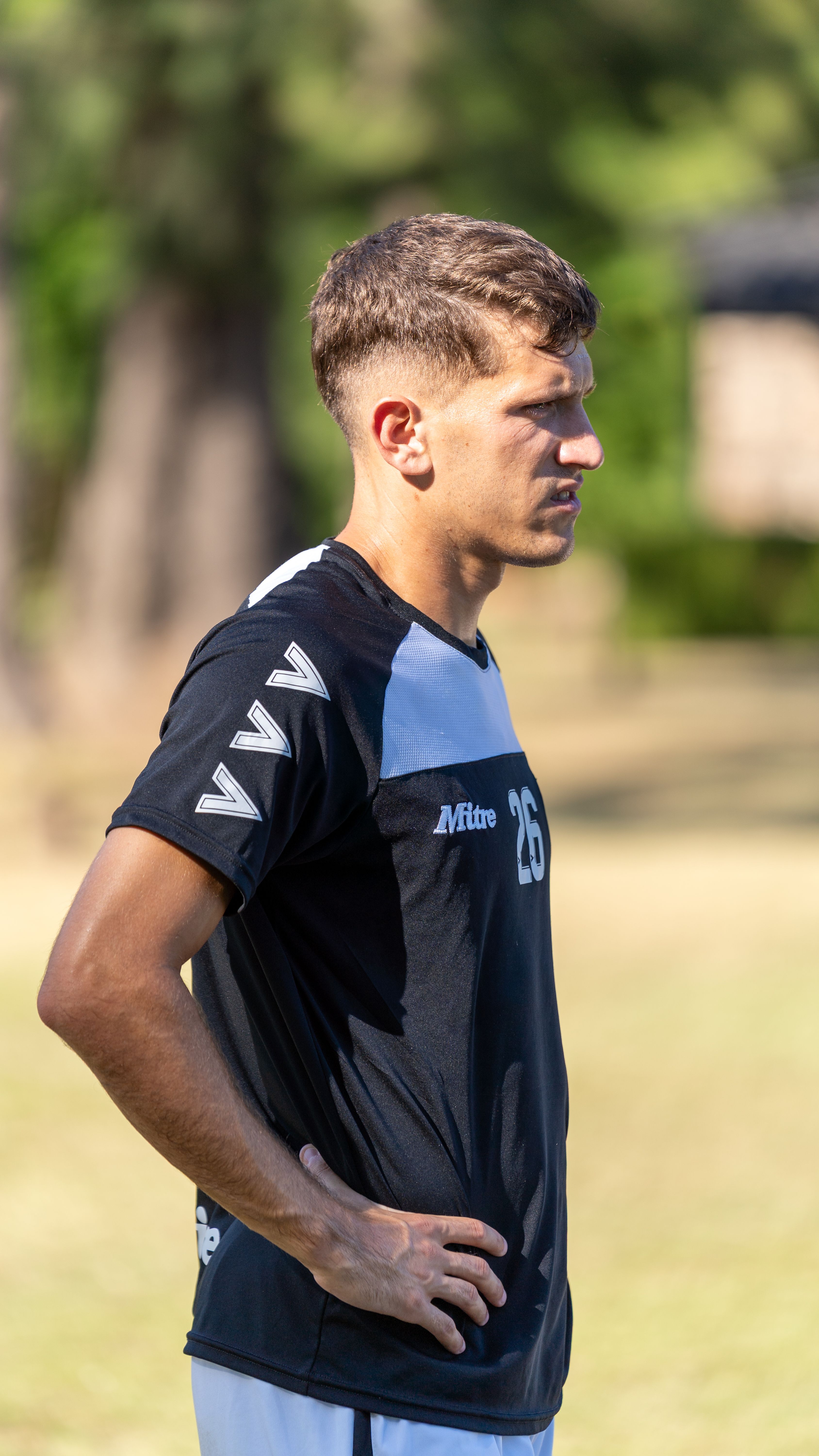 A focused male athlete standing outdoors during day training session.