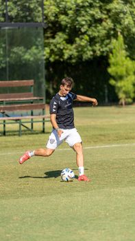 A young male soccer player kicks a ball on a sunny day, showcasing athletic skill on the field.