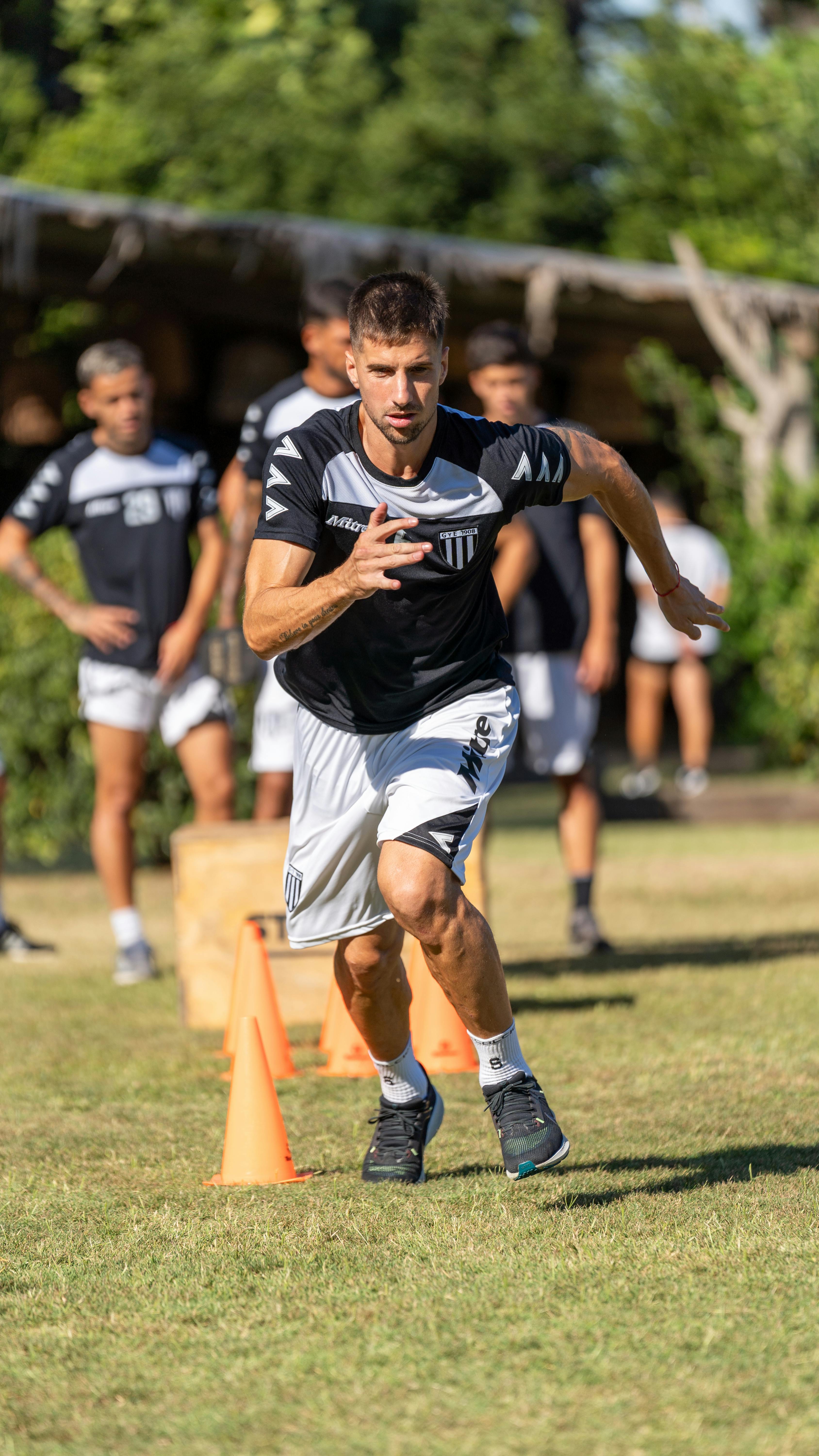 Male athlete performing agility drills with cones during a sunny day outdoor training.