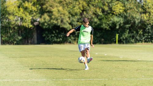 Free A young male soccer player practicing dribbling on an outdoor field on a sunny day. Stock Photo