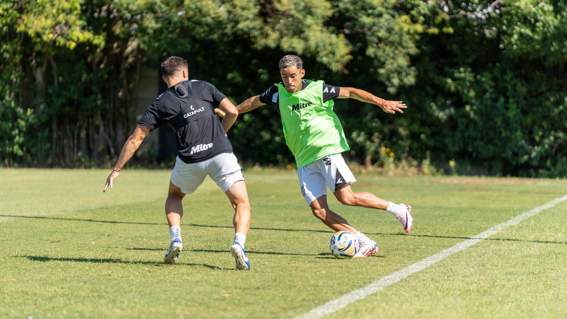 Two soccer players in action during a training session on a sunny day, showcasing agility and skill.