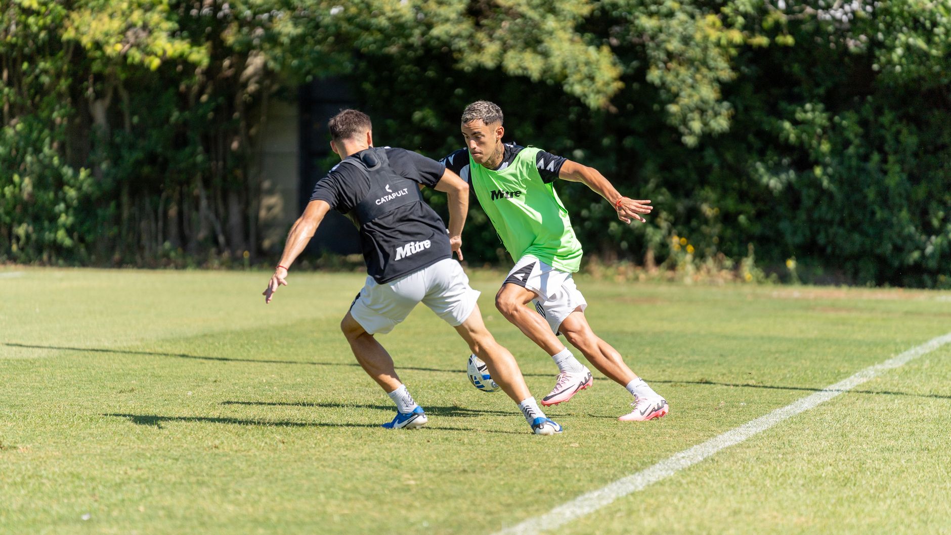 Defensive football drill with two players sprinting through agility ladders under a coach’s whistle