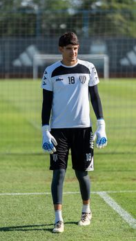 A male goalkeeper in training gear standing on a soccer field ready for practice.