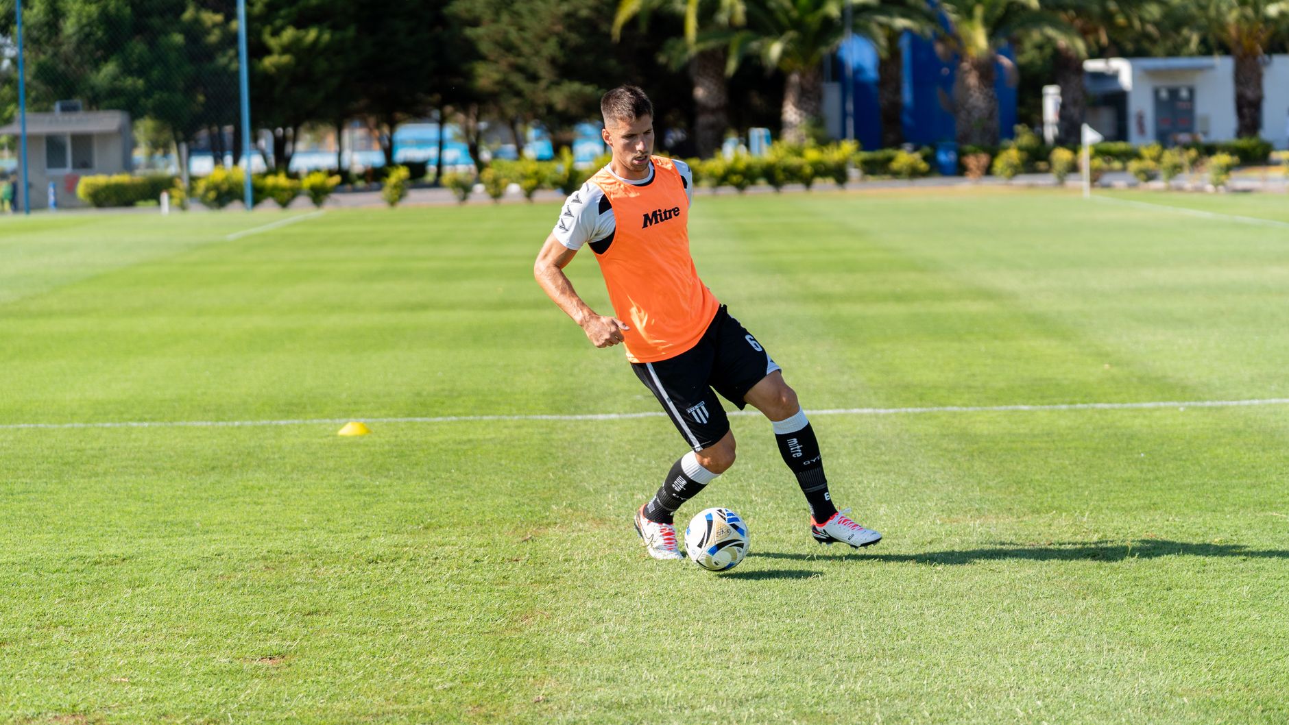 A male soccer player practicing on an outdoor field, focusing on ball control.
