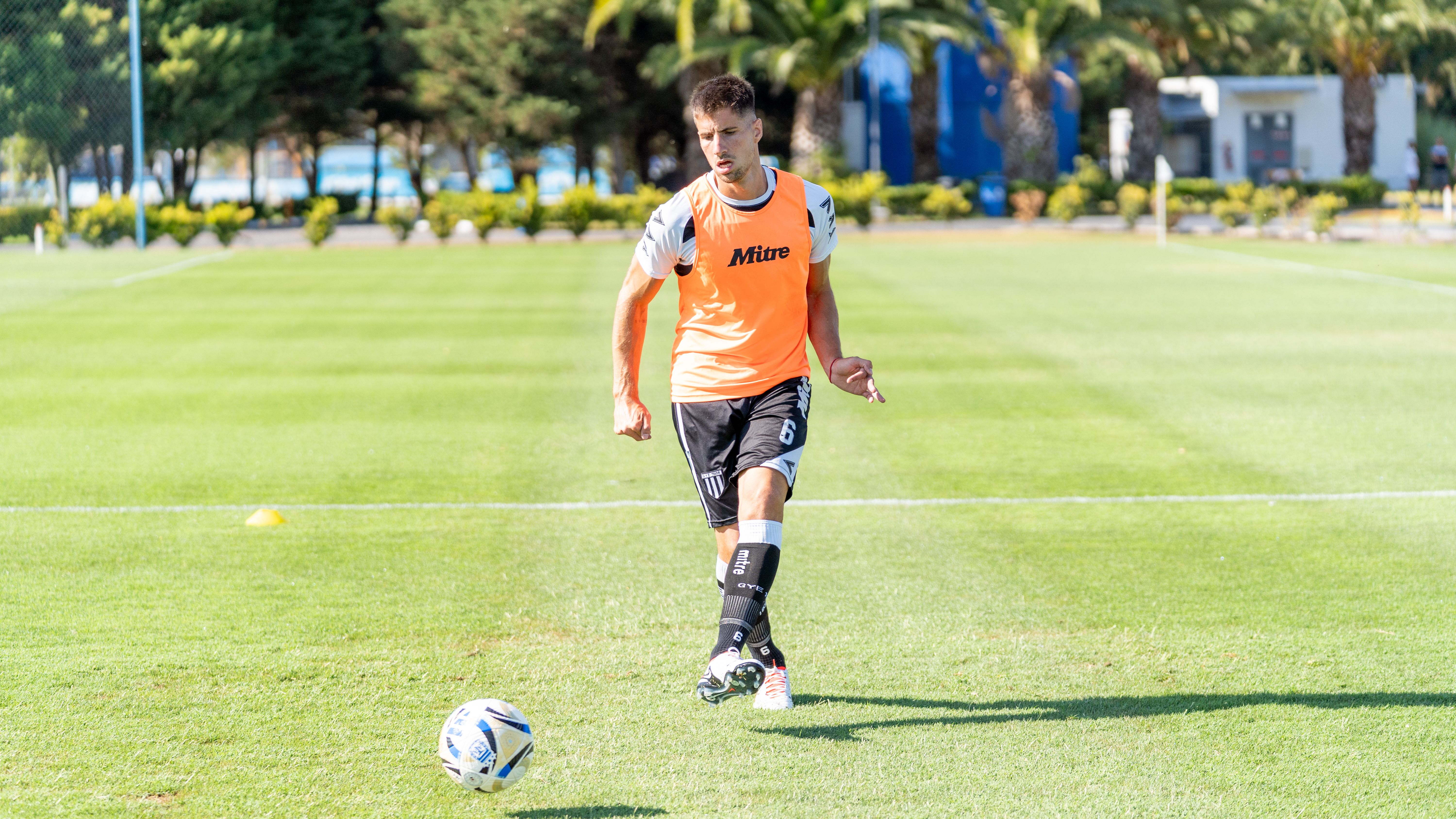 A young male soccer player in training, dribbling on a grassy outdoor field.