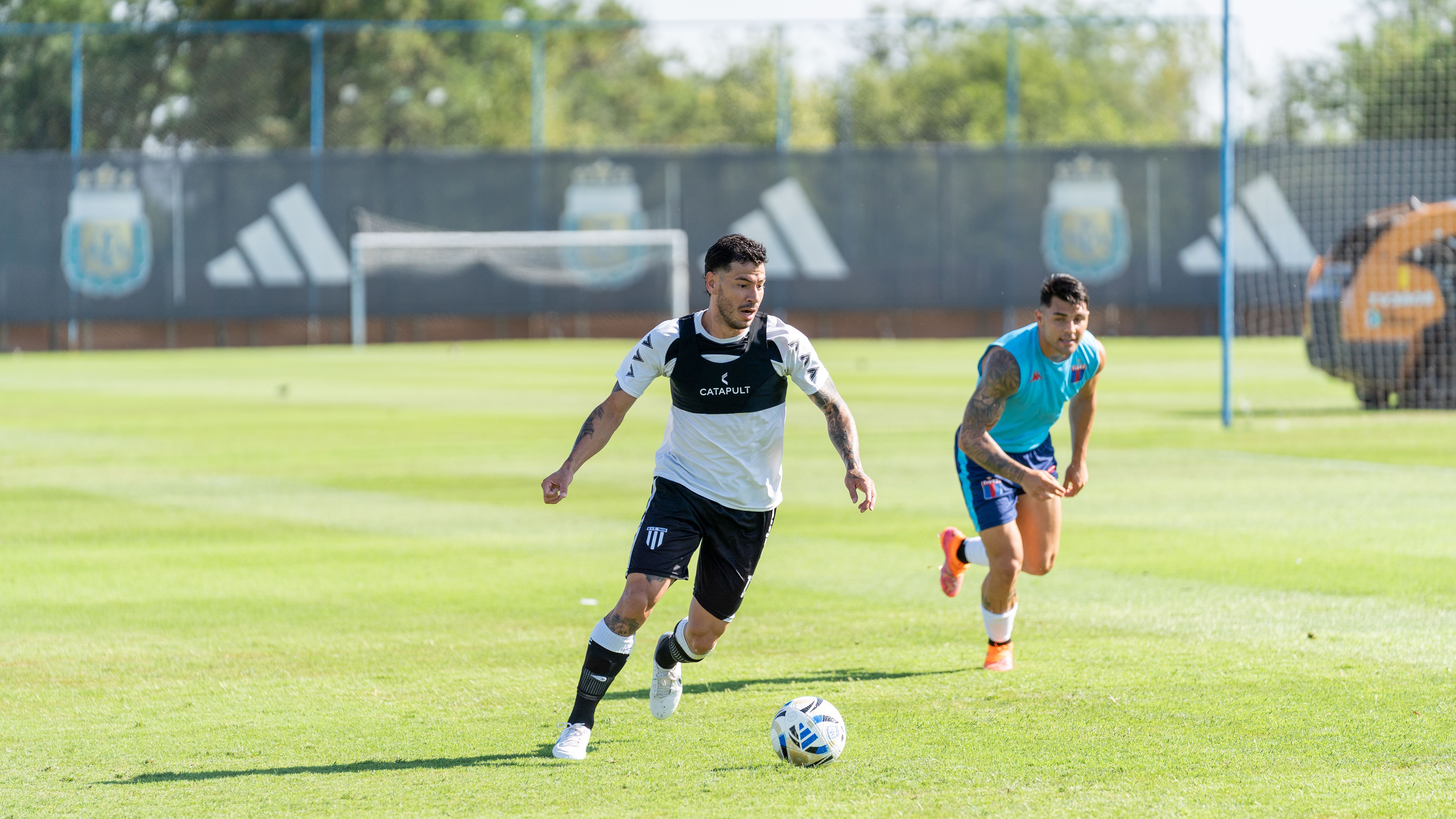 Two soccer players engaged in a dynamic training session on a sunny day outdoors.