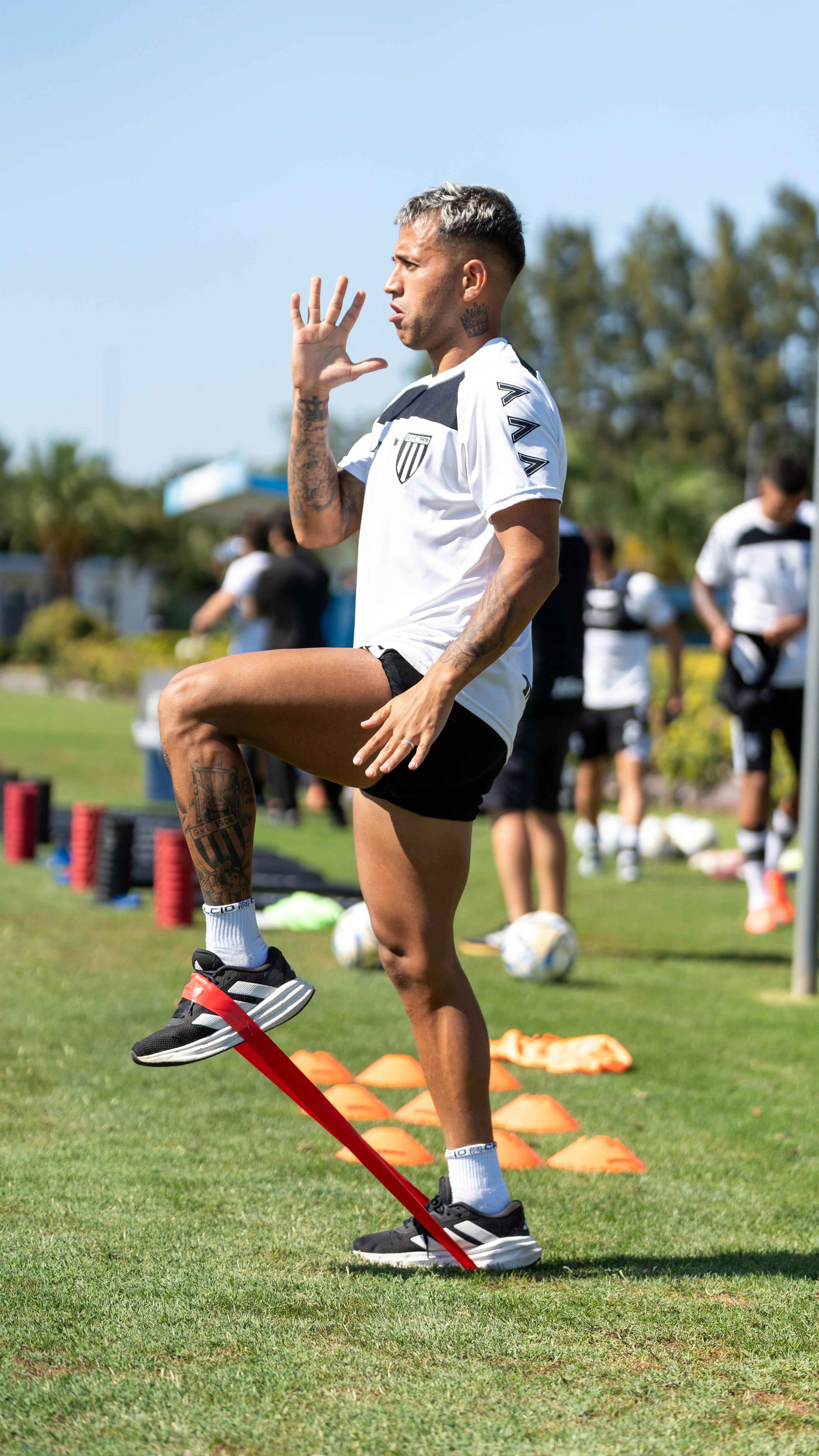 Soccer player exercising with resistance band during outdoor training session, demonstrating fitness and agility.