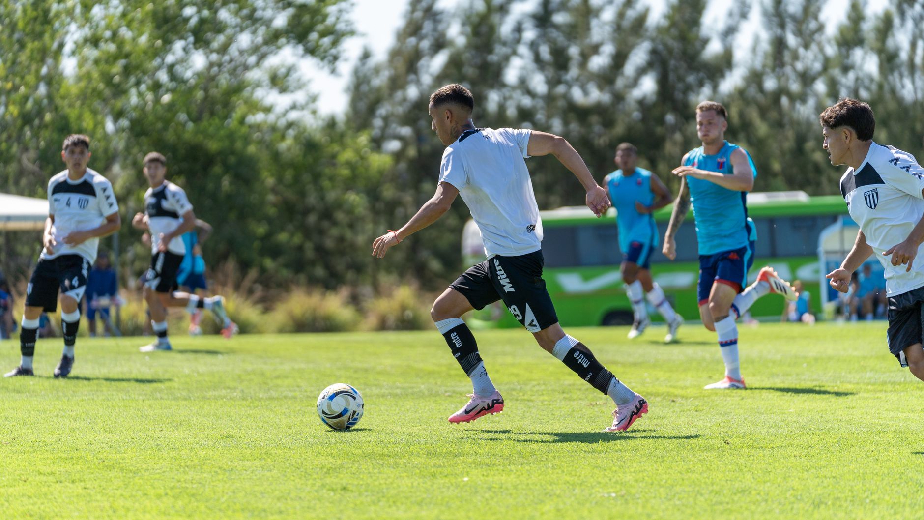 Players engaged in a competitive soccer match outdoors on a sunny day.