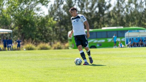 Free Young soccer player dribbles the ball during a sunny outdoor match. Stock Photo