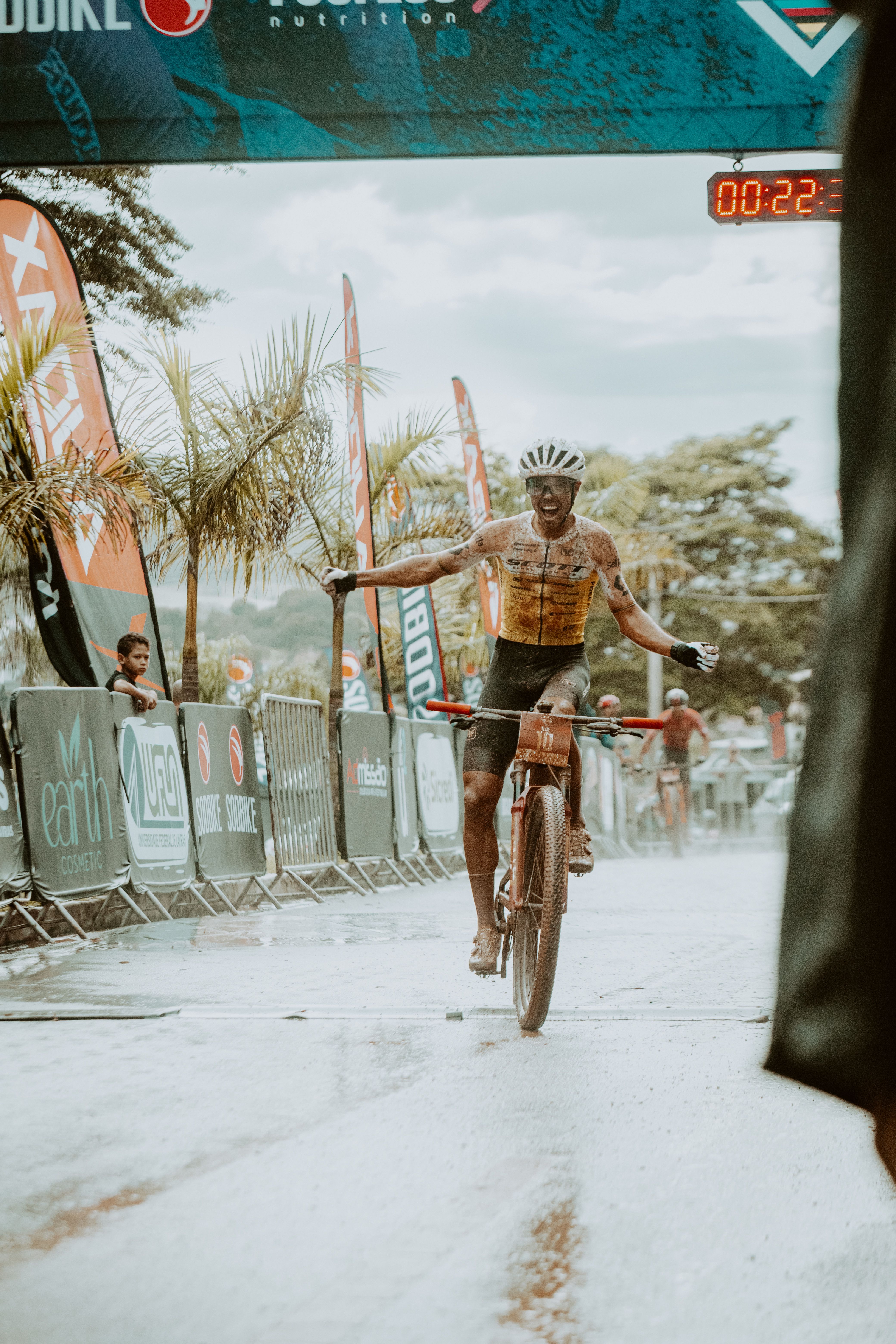 Cyclist celebrates victory as he crosses the finish line in a vibrant outdoor race event.