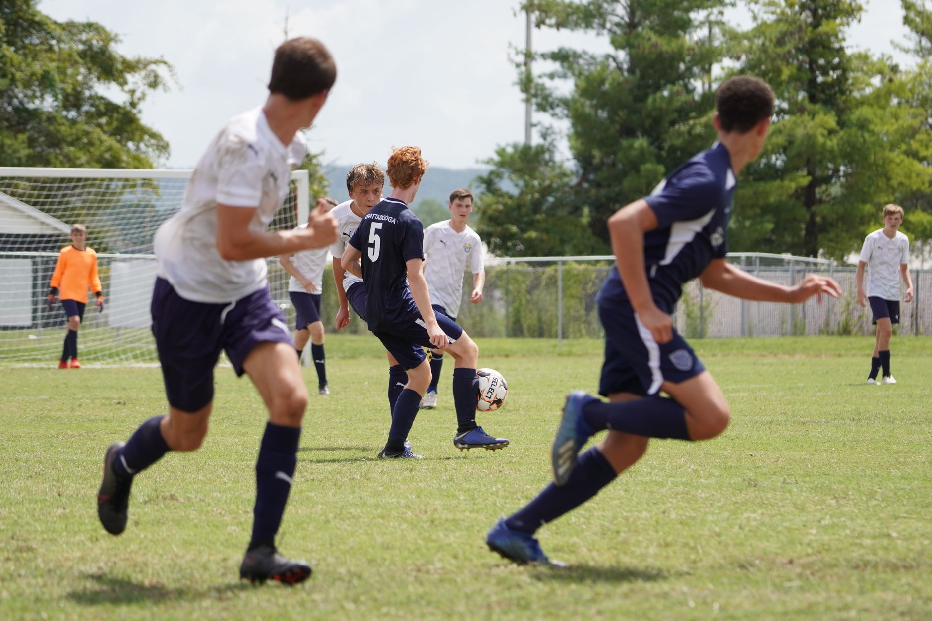 A vibrant outdoor soccer game featuring teenage players showcasing their skills on a bright, sunny day.