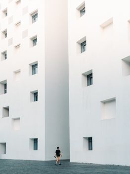 A person walks beside a modern white building with a minimalist design.