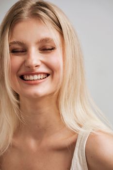 Close-up portrait of a smiling woman with blonde hair in natural light.