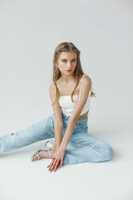 Fashionable young woman in casual outfit posing indoors with braids and stylish clothing.