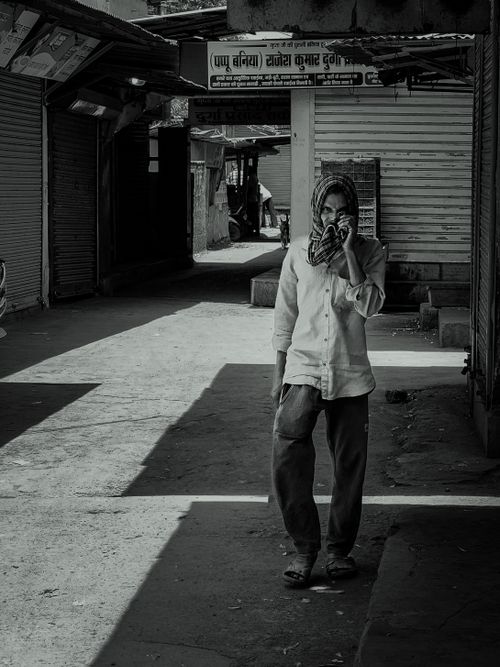 Free Black and white photo of a man walking in an empty street while talking on a phone. Stock Photo