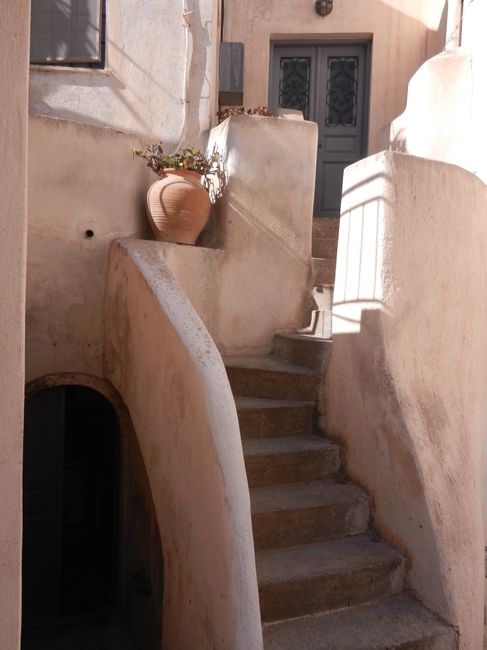 Charming rustic staircase with a clay pot under sunlight, exuding Mediterranean charm.