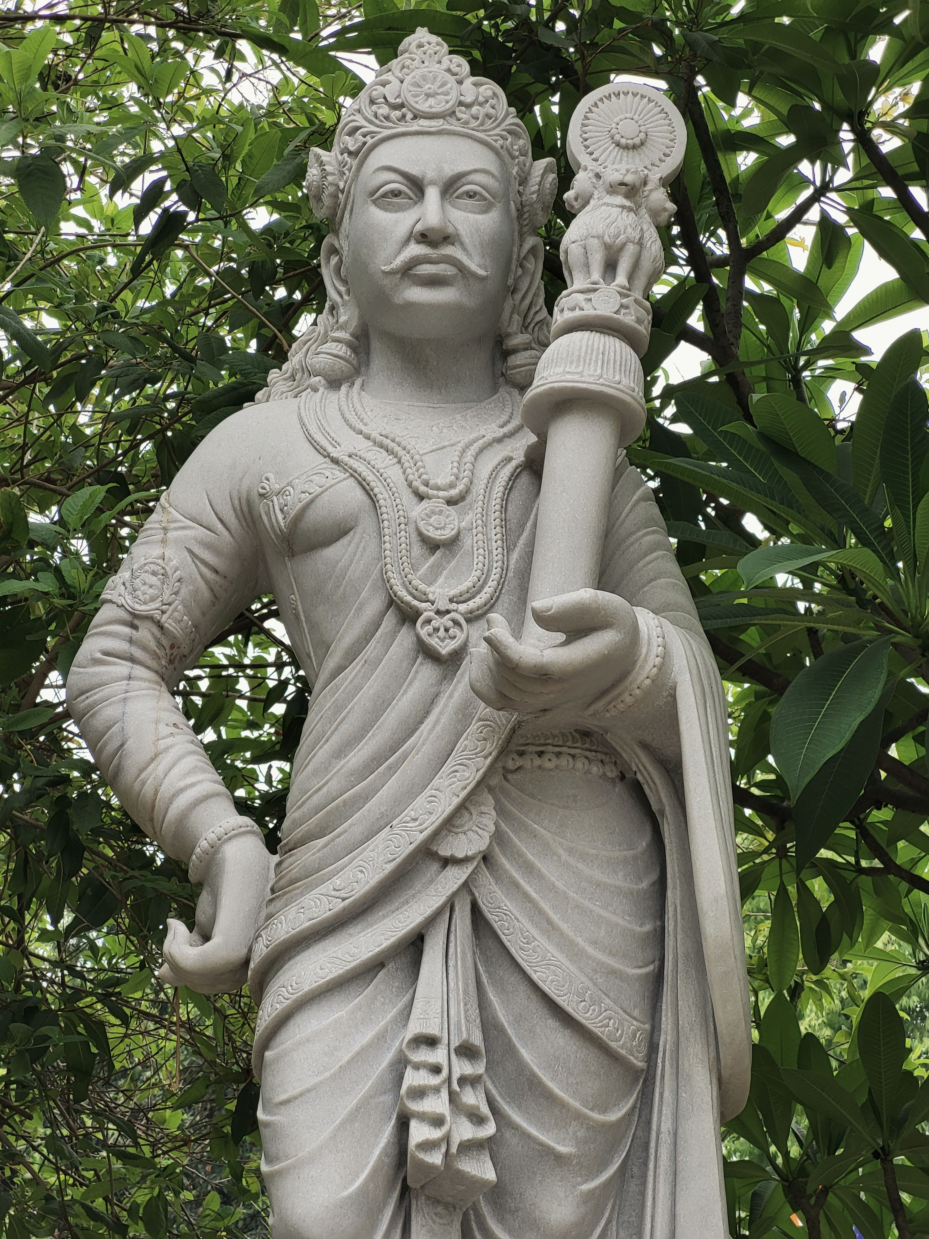 A detailed stone statue amidst lush greenery in Varanasi, India, showcasing traditional craftsmanship.