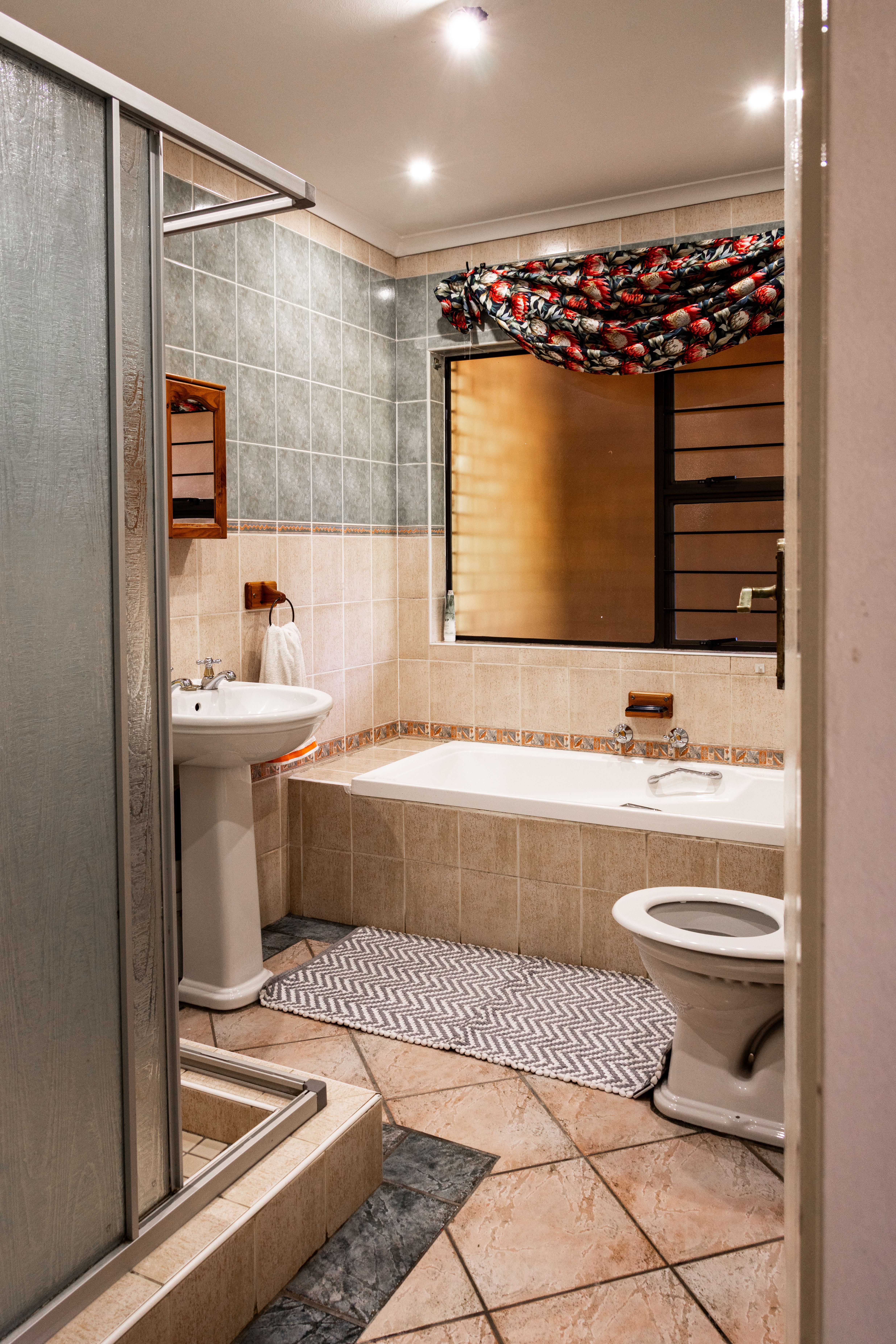 A cozy modern bathroom featuring a shower, bathtub, and toilet with ample lighting.
