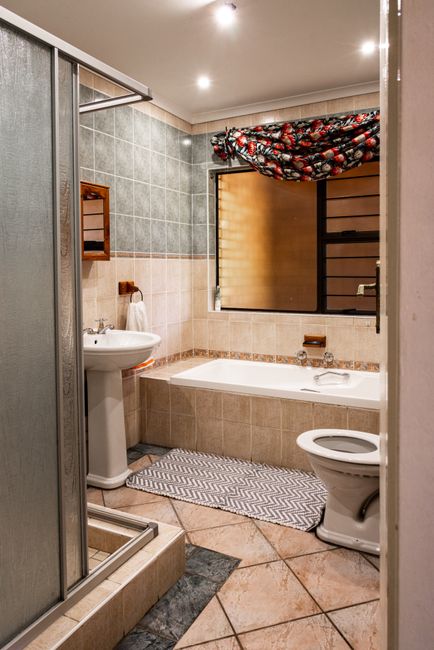 A cozy modern bathroom featuring a shower, bathtub, and toilet with ample lighting.