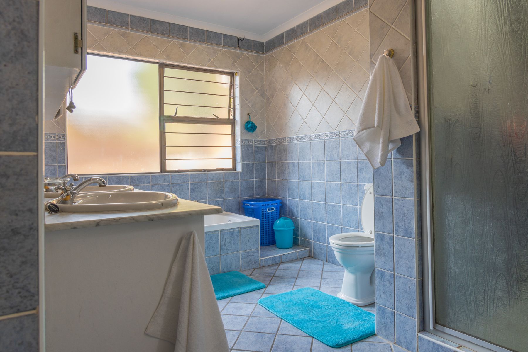 Spacious modern bathroom with blue tiled walls, white sanitaryware and natural light