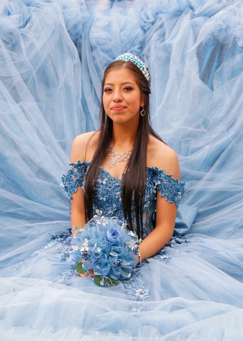 Free A young woman celebrating her quinceañera in a beautiful blue gown with floral details. Stock Photo