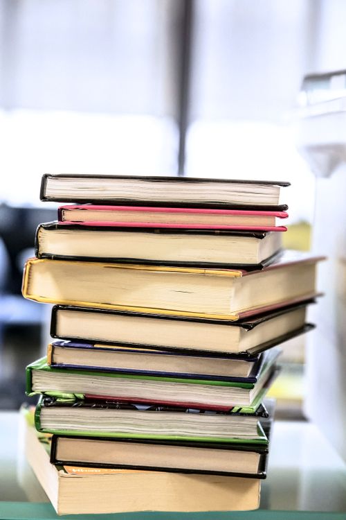 Free Vibrant stack of hardcover books on a glass table indoors, symbolizing knowledge and education. Stock Photo
