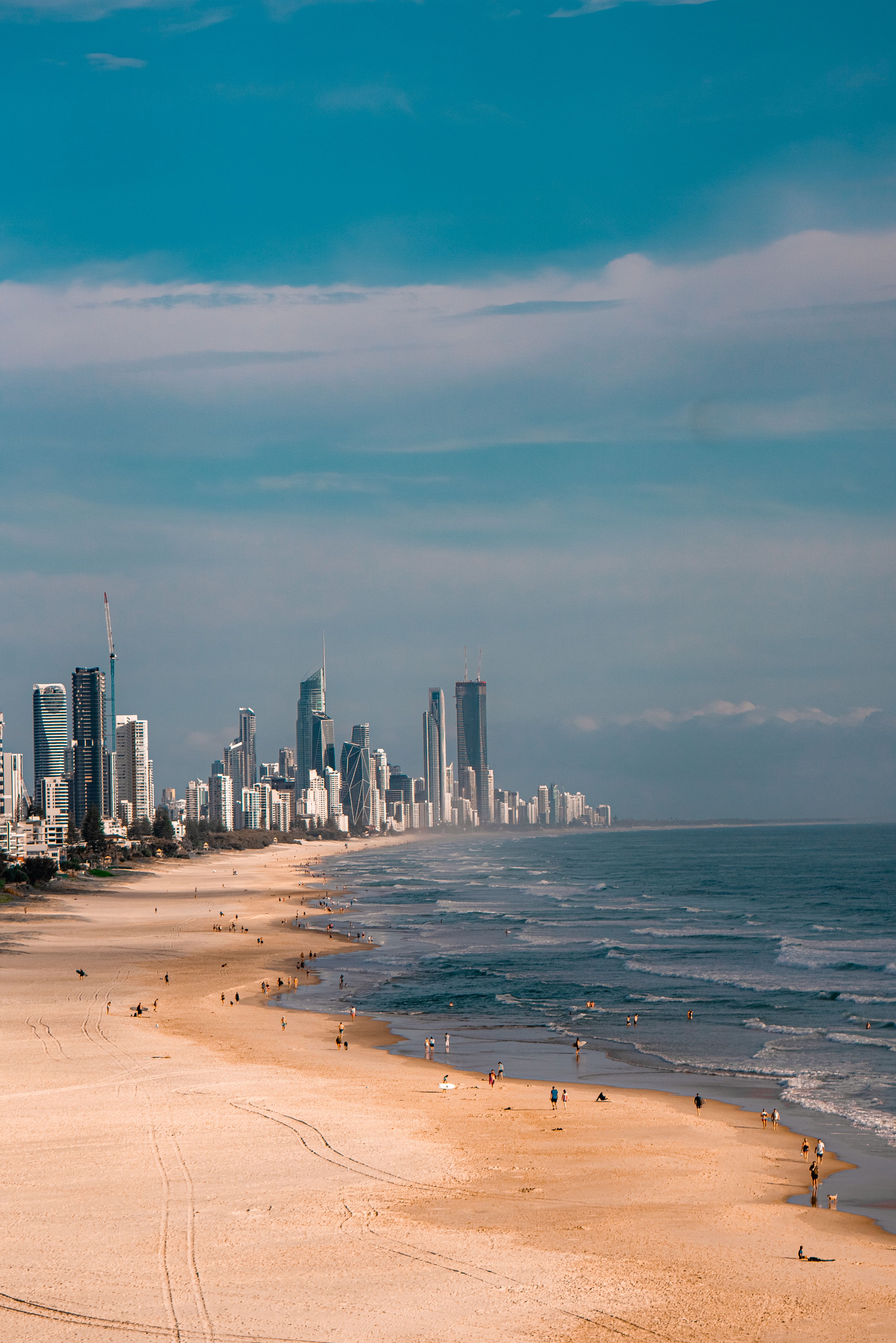 A stunning view of a coastal city's skyline with a sandy beach and people enjoying the day.