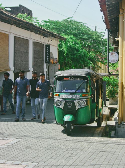 Free A vibrant street in Galle, Sri Lanka featuring a traditional tuk-tuk and pedestrians on a sunny day. Stock Photo