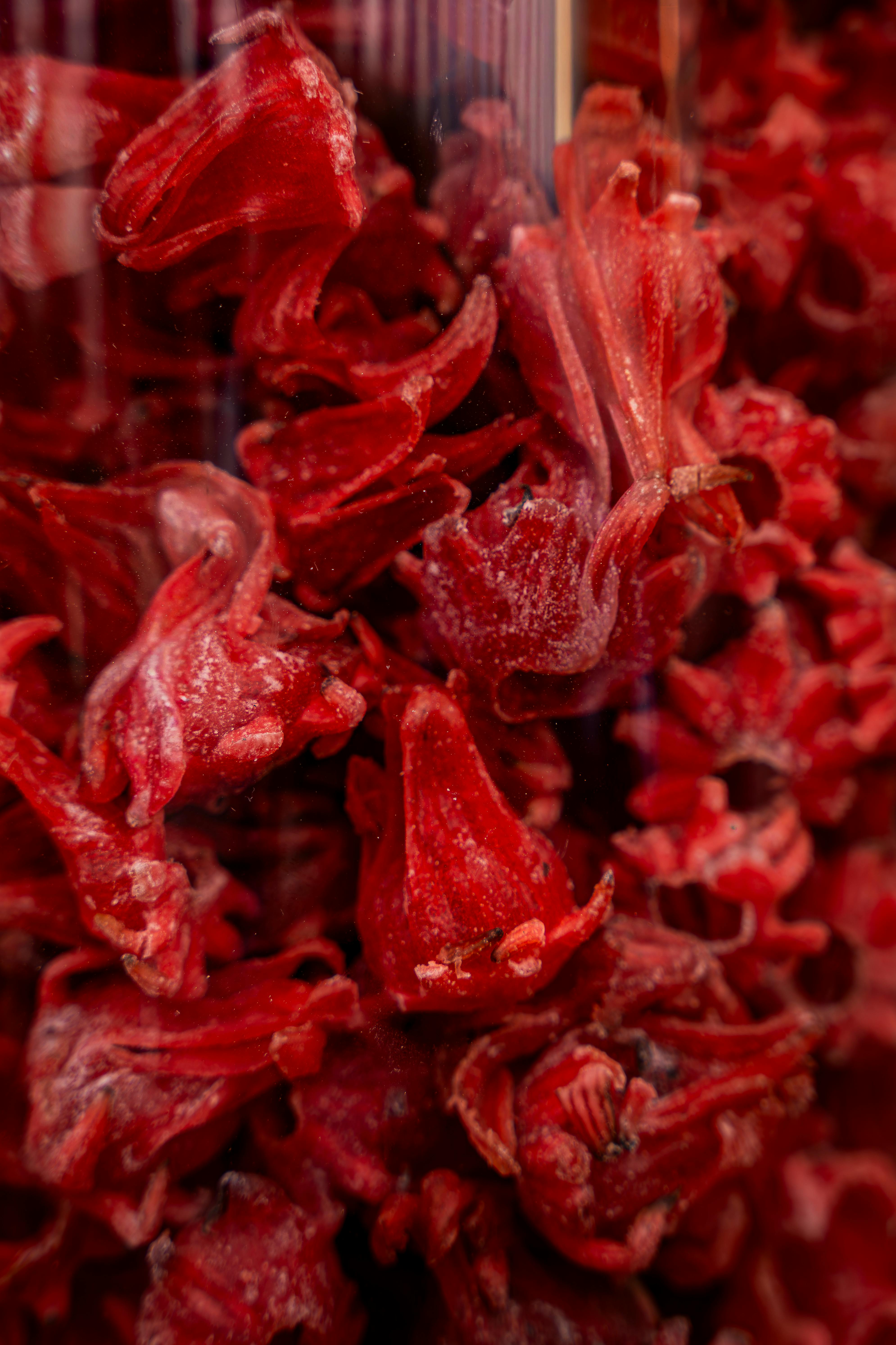 Vivid close-up of fresh red roselle hibiscus flowers in a market setting.
