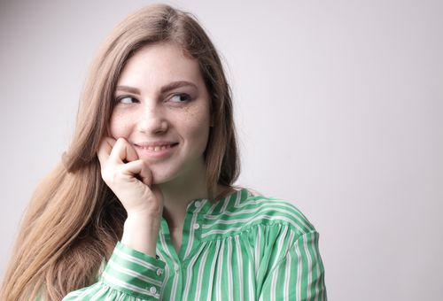 Free Portrait of a smiling woman in a green striped top, looking away with a thoughtful expression. Stock Photo