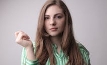 一位穿着绿色条纹衬衫的年轻女子深思熟虑的肖像，表达了自信