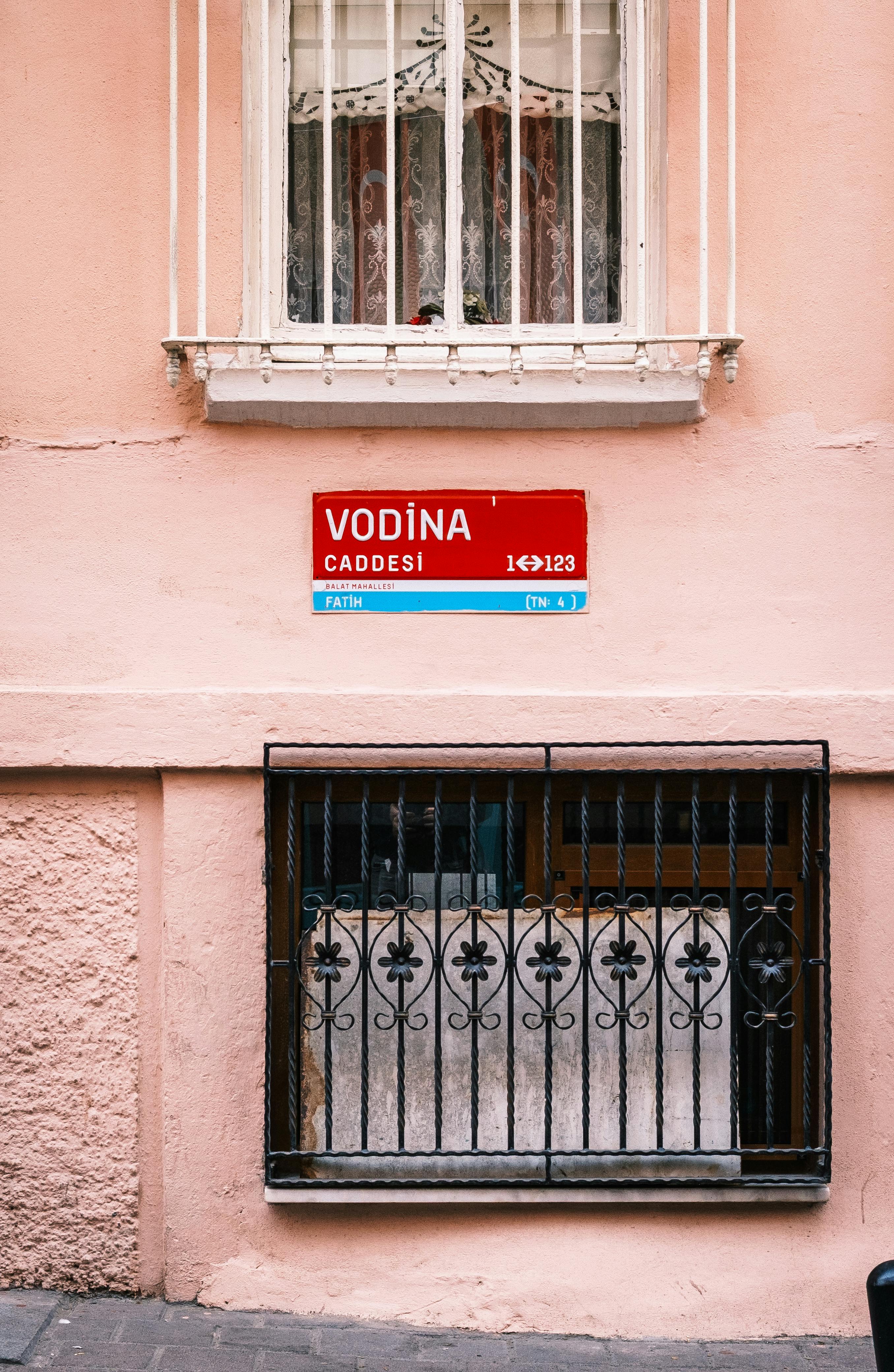 Street sign 'Vodina Caddesi' on a charming pastel pink building in Istanbul, Turkey.