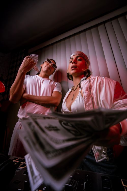 Free Stylish young adults in urban setting holding cash, exuding a modern, confident vibe. Stock Photo
