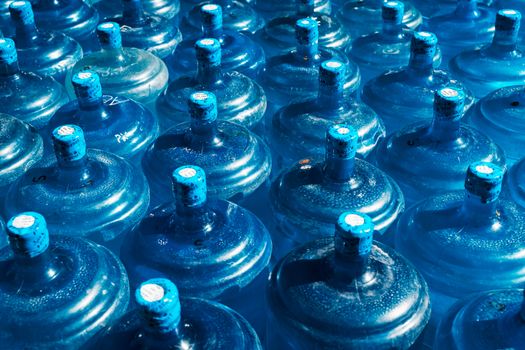 Top view of multiple blue water bottles arranged closely. Unique abstract pattern and bright colors.