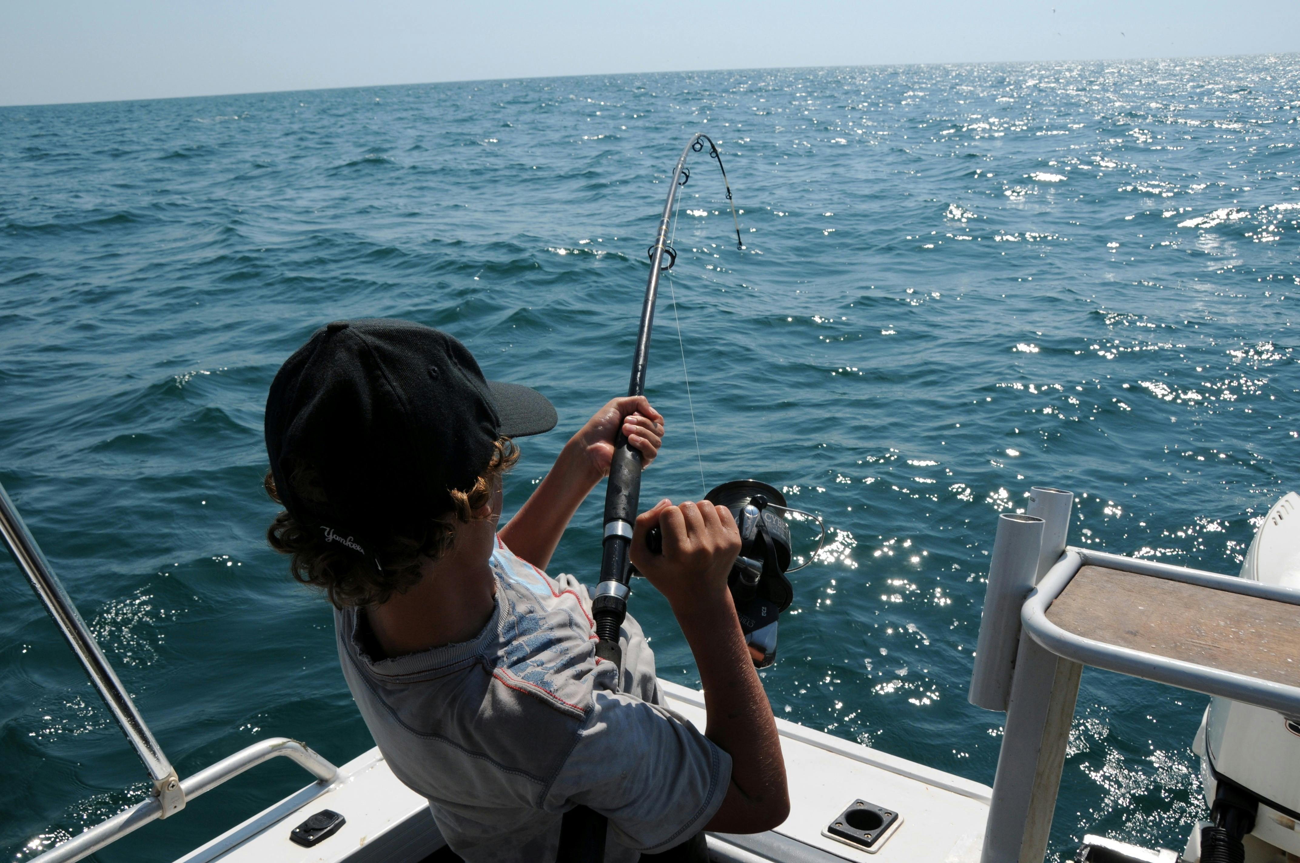 Man fishing from the boat on the ocean. | Photo: Pexels