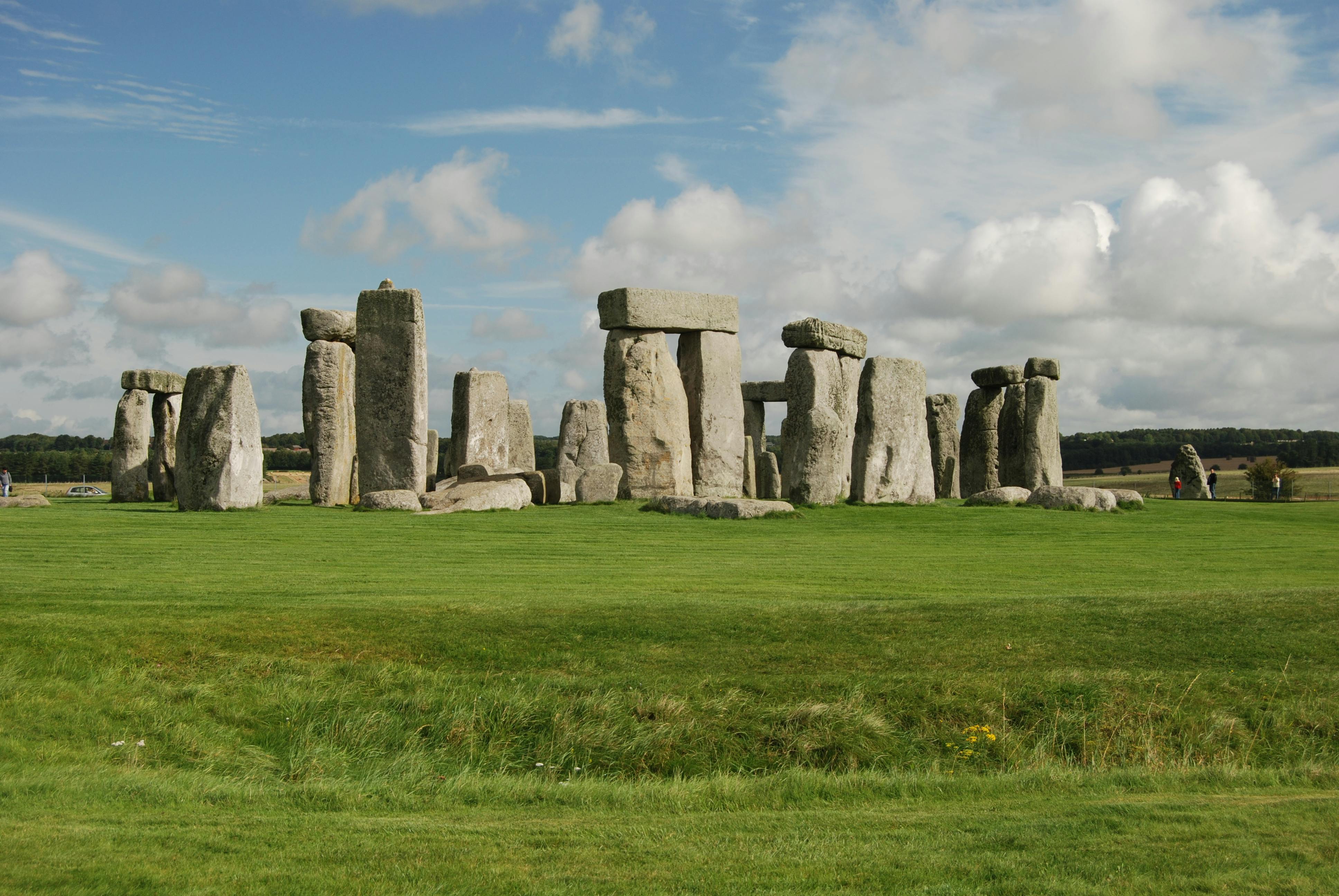 gray rock formations on green grass field under blue sky