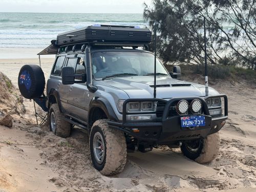 Free 4x4 SUV navigating sandy terrain on a scenic Australian beach, showcasing adventure and rugged travel. Stock Photo
