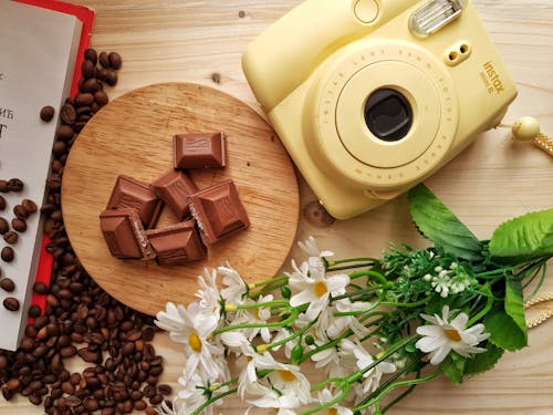 무료 초콜릿 근처에있는 즉석 사진 카메라와 실내에 쏟은 커피 원두 스톡 사진