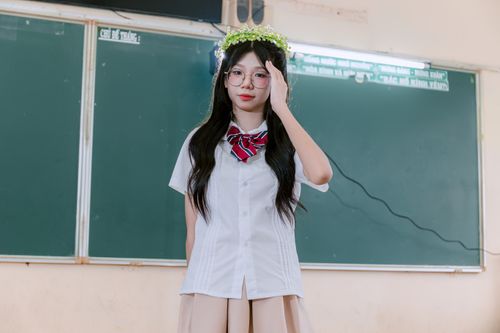 Free Young woman in school uniform wearing a floral crown, standing in a classroom. Stock Photo